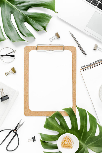 Home office workspace mockup with laptop, tropical leaves Monstera, clipboard, notebook and accessories on white background. Flat lay, top view - Fotó, kép