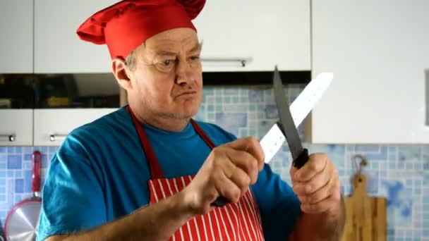 Старший дорослий кухар кавказької етнічності в кухарях капелюх гострий ніж на ножі на домашній кухні. Крупним планом
. - Кадри, відео