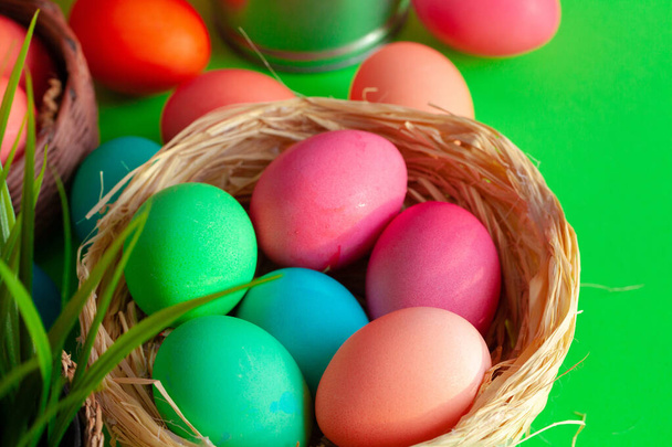 Uova colorate vibranti in un nido su verde. Concetto pasquale - Foto, immagini