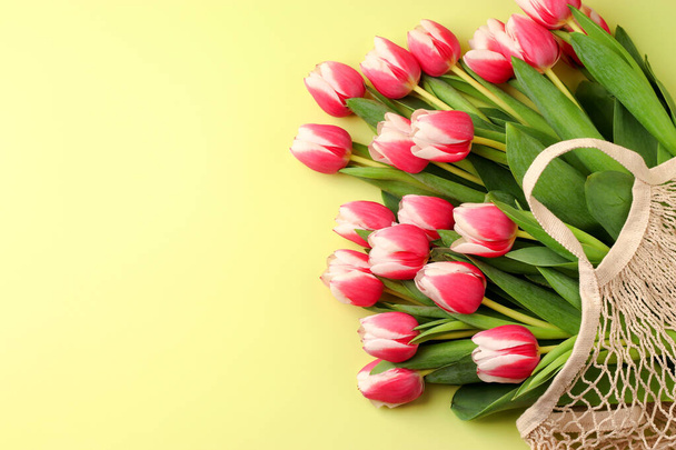 Um buquê de flores de primavera tulipas em um saco de corda em um fundo leve. Dia das mulheres, conceito do Dia dos Namorados, Dia das Mães. Embalagem ecológica. Deitado. Espaço de cópia. - Foto, Imagem