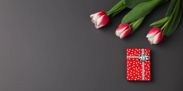 Banner. Bouquet of tulips, gift boxes on a dark background. Festive concept for Valentine's Day, Mother's Day, Women's Day and Birthday. Flatlay, copy space - Фото, зображення