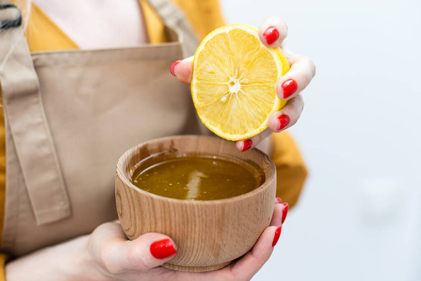 oříznutý pohled ženy míchání medu s citronem na bílém pozadí. - Fotografie, Obrázek