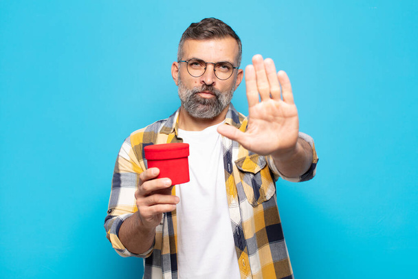 adult man looking serious, stern, displeased and angry showing open palm making stop gesture - 写真・画像