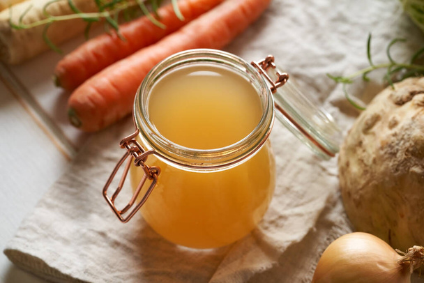 Beef bone broth in a glass jar with fresh vegetables - Photo, Image