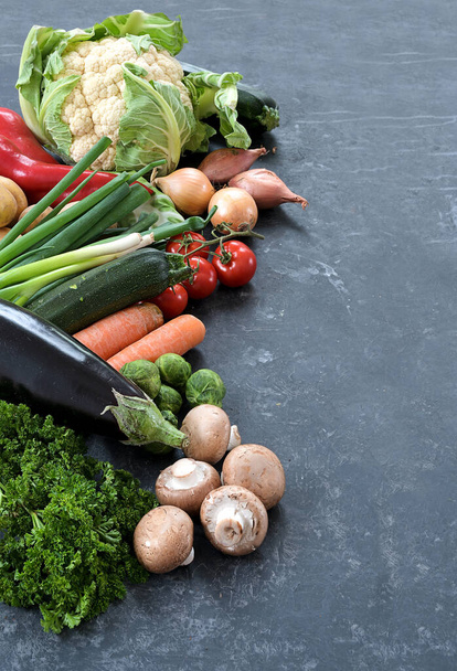 Fresh vegetables like mushrooms, carrots, cauliflower and more on a dark gray slate background, healthy food for fitness and diet, copy space, vertical, selected focus - Fotó, kép