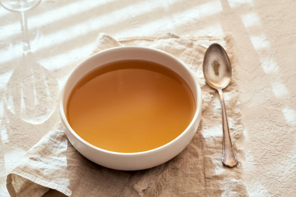 A bowl of beef bone broth on a bright background - Photo, Image
