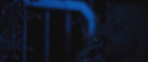 Soldado adulto deprimido fumando un cigarrillo afuera por la noche, lidiando con ansiedad y trauma post. TEPT, depresión, concepto de salud mental. Primer plano, cámara lenta, iluminación azul. - Metraje, vídeo
