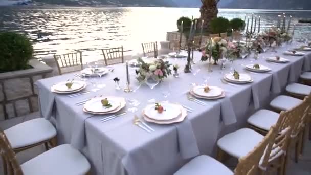 Стол на свадебном банкете, украшенный цветами, подсвечниками и молодыми гранатами на пирсе в Которском заливе - Кадры, видео