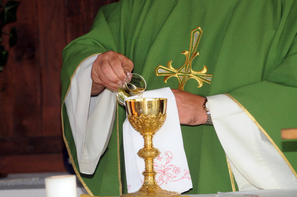 een priester bij een communie ceremonie in de katholieke kerk - Foto, afbeelding