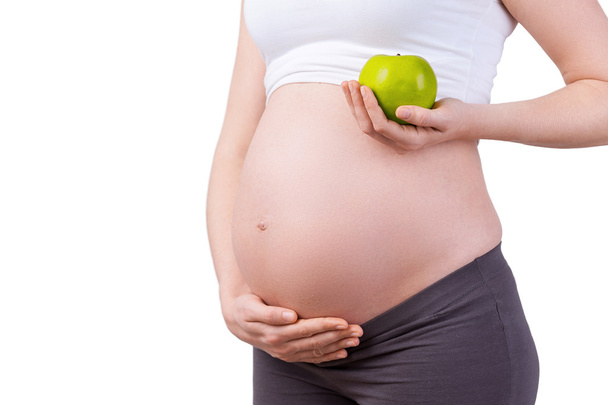 Pregnant woman holding green apple - Foto, afbeelding