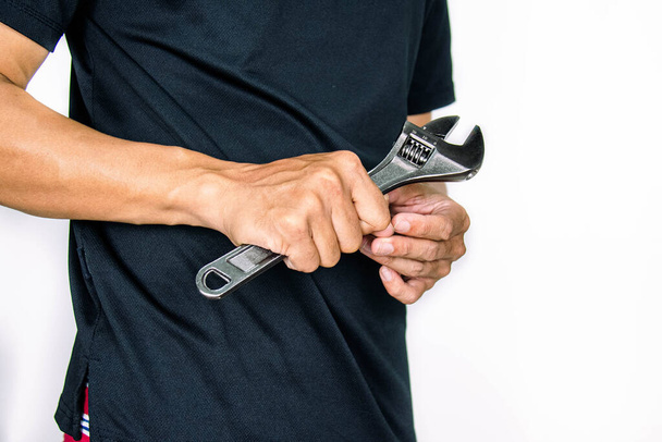 Plumber wearing black shirt holding adjustable wrench. Isolated on white background. copy space - Valokuva, kuva