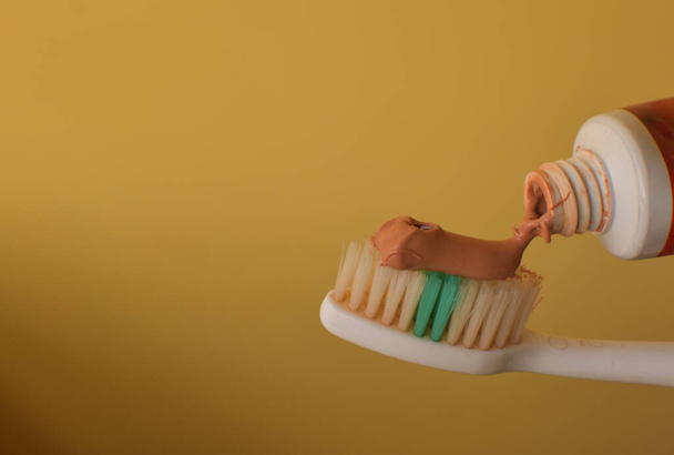 Οδοντόβουρτσα με κόκκινη αγιουρβεδική οδοντόκρεμα. Κοντινό πλάνο της κόκκινης οδοντόκρεμας συμπιέζεται σε οδοντόβουρτσα σε καθαρό φόντο με αντίγραφο χώρο. - Φωτογραφία, εικόνα