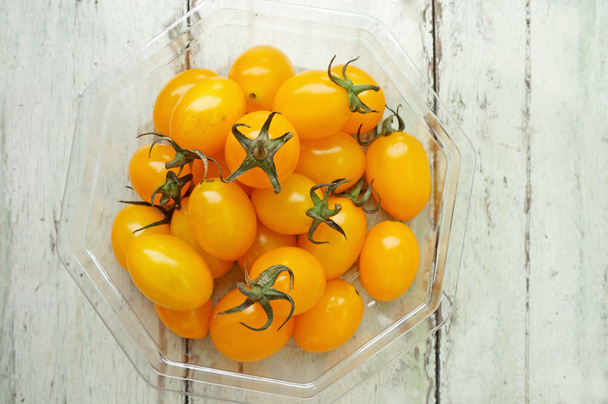 gele cherry tomaten in plastic verpakkingen op de tafel - Foto, afbeelding