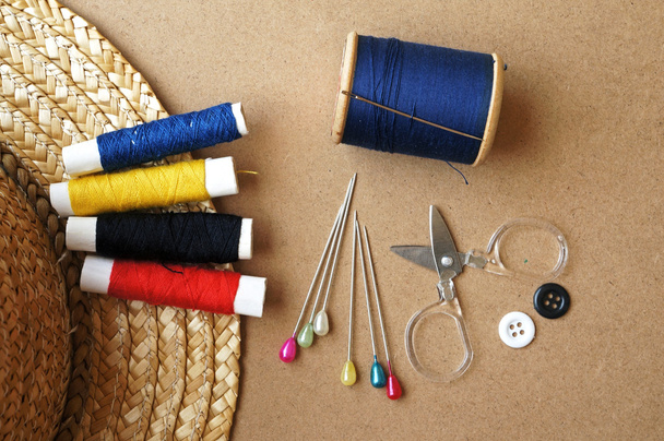 naaien items: knoppen, kleurrijke stoffen, schaar, meten tape, vingerhoed, spoelen van draad op naaien patroon - Foto, afbeelding