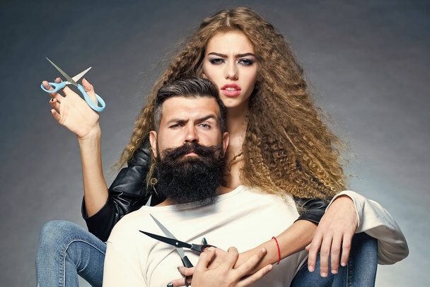 Couple of long-haired young woman holding scissors. Bearded man with moustache in barber shop. Sexy barbershop concept. Barber with beard. - Φωτογραφία, εικόνα