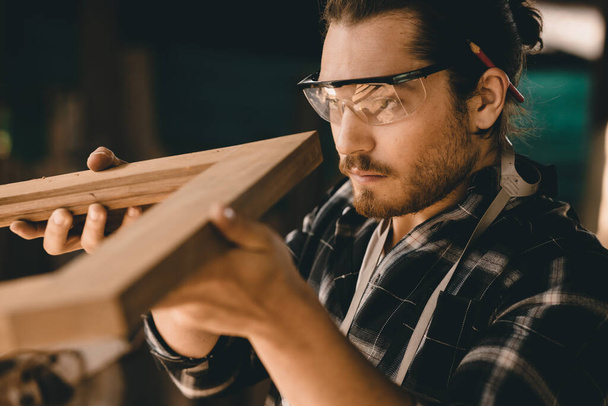 Ξυλουργός άνθρωπος επαγγελματίας ειδικευμένος στην εργασία ξύλου αναζητούν λεπτομέρεια του αριστουργήματος ξυλογλυπτική στο εργαστήριο επίπλων - Φωτογραφία, εικόνα