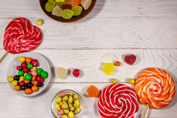 Цветные шоколадные конфеты, леденцы и конфеты на белом деревянном столе - Фото, изображение