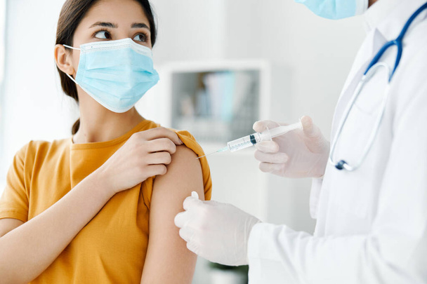 пациент в больнице и врач в защитных перчатках вводят вакцину в плечо женщины - Фото, изображение