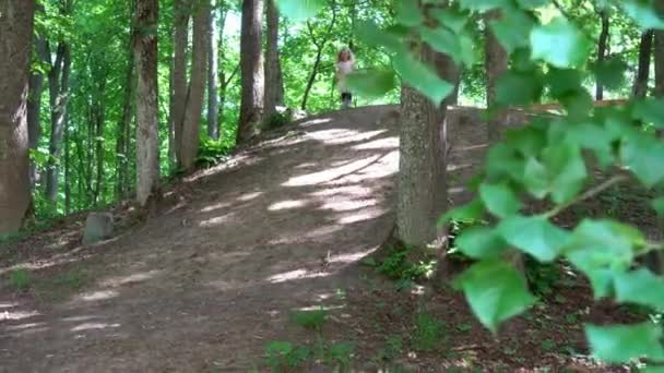 Fille heureuse en robe rose descendant la colline rapide dans le parc. Gimbal motion shot - Séquence, vidéo