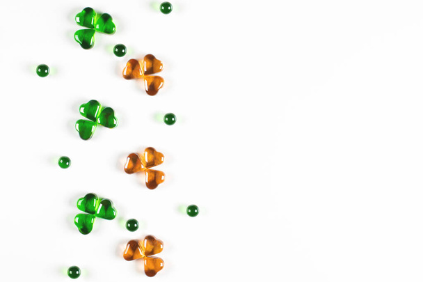 Símbolos de trébol hechos de corazones de vidrio verde y naranja sobre fondo blanco  - Foto, Imagen