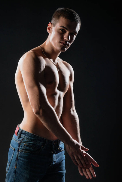 Portrait of a strong healthy handsome athletic man posing as a fitness model on dark background - Fotó, kép