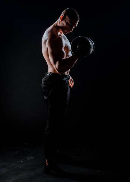 Hombre musculoso haciendo ejercicio en el gimnasio haciendo ejercicios con pesas, hombre fuerte - Foto, imagen