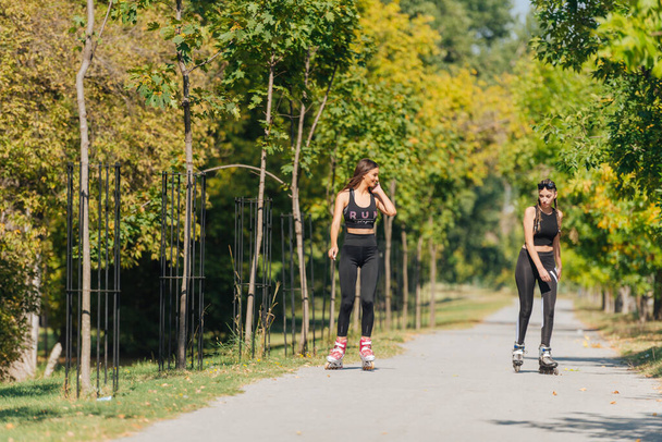 Imagen completa de las mujeres deportistas sexy patinaje sobre ruedas en el parque - Foto, imagen