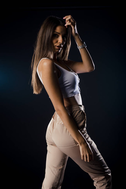 Stylish fashion girl posing in trendy clothes against dark background - Фото, зображення
