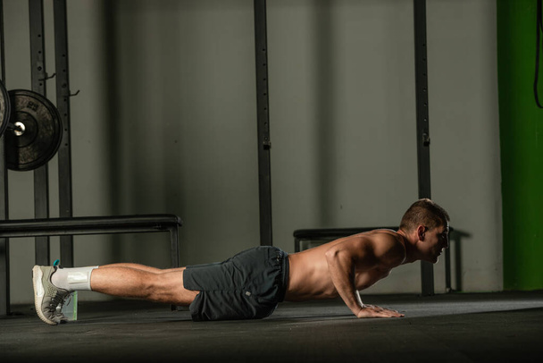 Strong male athlete doing push-ups indoors. Close up perspective, healthy lifestyle, fatless body. - Photo, Image