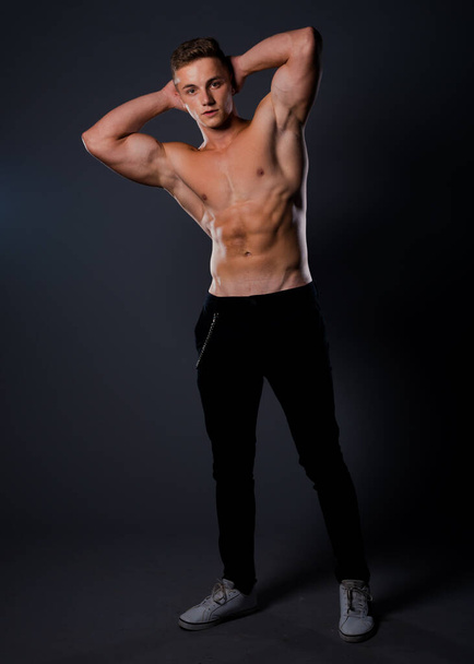 Portrait of a handsome muscular man posing against black background - Foto, Imagem
