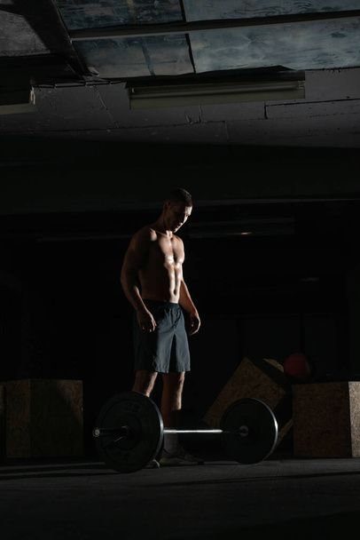 Silhouette di un forte atleta a torso nudo in forma che fa squat. Concetto di sollevamento pesi. - Foto, immagini