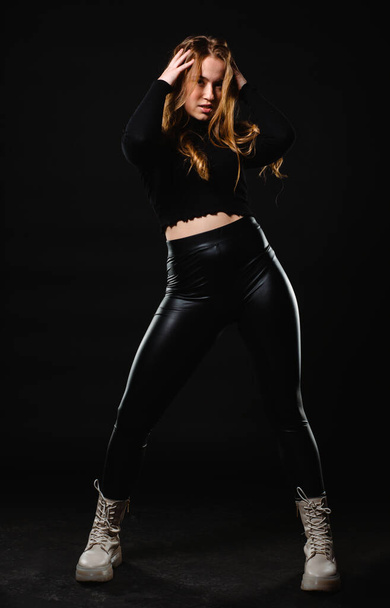 Retrato de uma bela jovem mulher sensualidade adulta vestindo top tanque preto e calças de látex isolado no fundo escuro - Foto, Imagem
