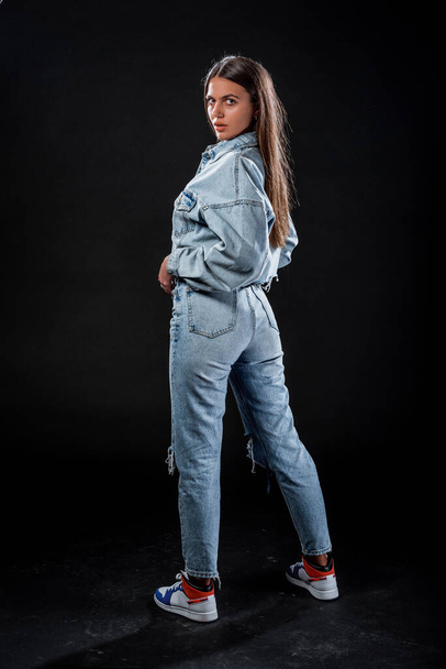 Portret van een mooi stijlvol meisje met blauwe gescheurde jeans en bijgesneden denim jas - Foto, afbeelding