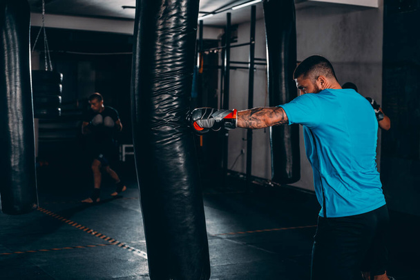 Дорослий боксер в боксерських рукавичках тренування з боксерським мішком у спортзалі
 - Фото, зображення