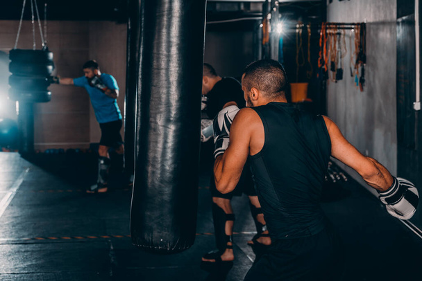 Eltökélt fiatal Muay Thai harcos bokszkesztyűben edzés thai boksz bokszzsák - Fotó, kép