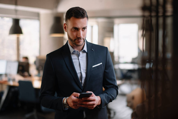 Businessman in suit using modern smartphone in the office. - Zdjęcie, obraz