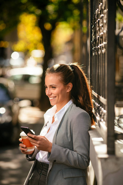 Young businesswoman on coffee break using phone - Foto, afbeelding