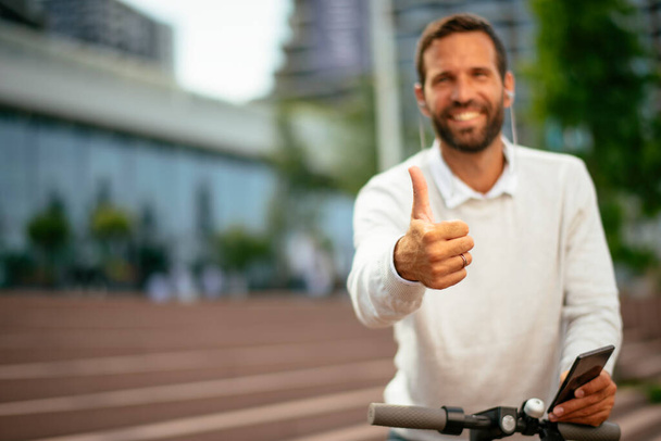 Businessman riding electric scooter. Man showing thumbs up. - Photo, Image