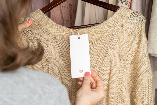Donna shopper in cerca di tag scegliendo maglione da vestiti in negozio di abbigliamento. Shopping. - Foto, immagini