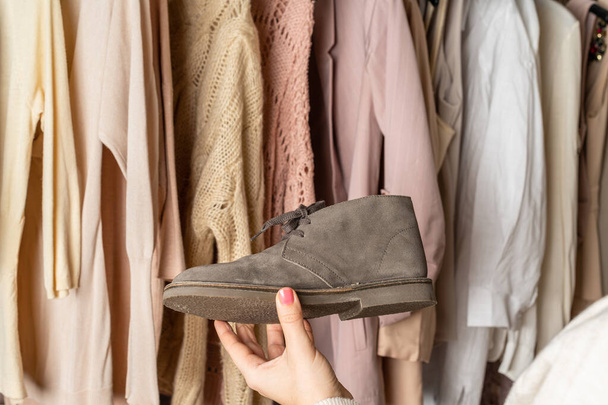 Woman choosing boots (shoes) and clothes in home cupboard. Season concept - Photo, Image