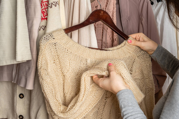 Woman choosing woolen sweater in home cupboard. Season concept - Photo, Image