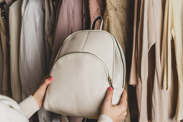 Woman choosing  small leather backpack, clothes in home cupboard. Season concept - Photo, Image