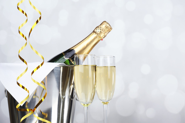 Glasses of champagne and bottle in pail on light background - Foto, immagini