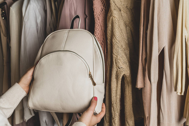 Woman choosing  small leather backpack, clothes in home cupboard. Season concept - Foto, imagen
