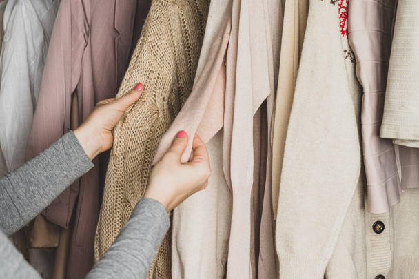 Woman comparing and choosing two different woolen sweaters in home cupboard. - 写真・画像