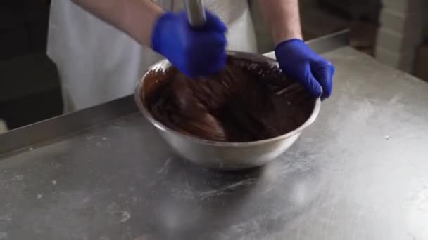 Ένας ζαχαροπλάστης ανακατεύοντας λιωμένη μαύρη σοκολάτα σε ένα μπολ, από κοντά. Ζεστή σοκολάτα. Ζαχαροπλαστική. Μαγειρική λιωμένη σοκολάτα - Πλάνα, βίντεο