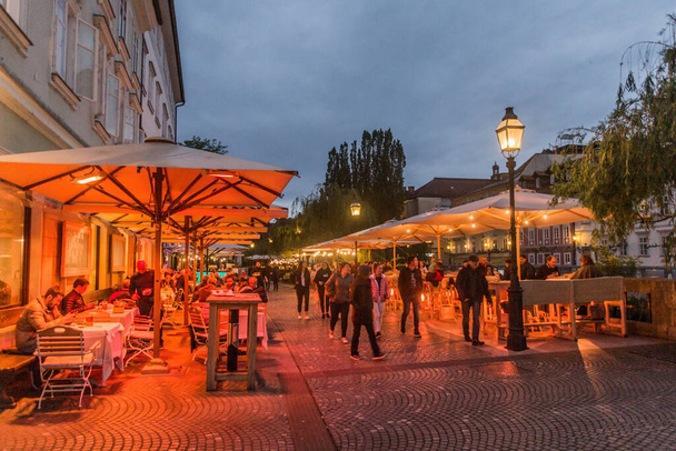 LJUBLJANA, SLOVENIA - MAY 13, 2019: Open air restaurants at Cankarjevo nabrezje riverside in Ljubljana, Slovenia - Zdjęcie, obraz
