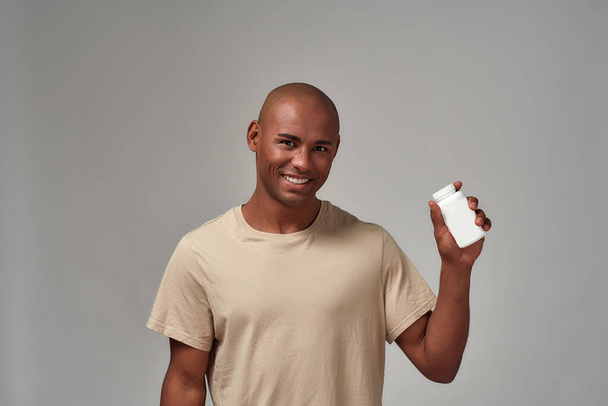 Display of a pill bottle in a joyful man arm - Foto, afbeelding