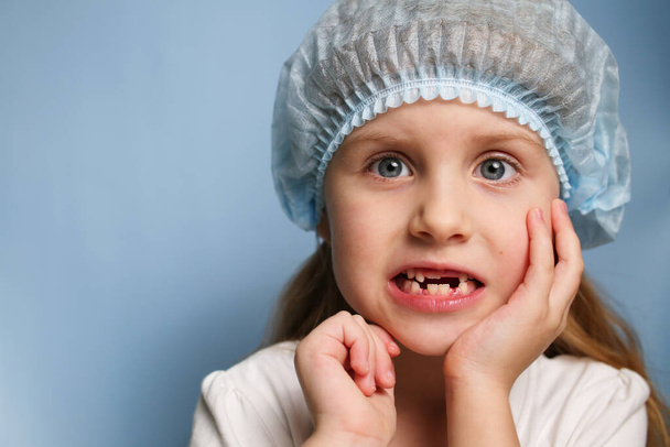 Een klein meisje bij de tandarts laat een tandeloze mond zien. Vervanging van tijdelijke tanden door permanente tanden bij een kind. Babytanden. Bezoek aan de tandarts. - Foto, afbeelding