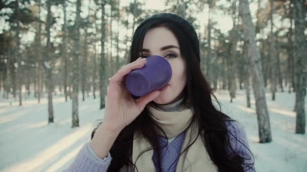 Mujer positiva en suéter caliente bebe té en el bosque de invierno - Metraje, vídeo